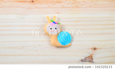 Cute handmade snail on a wooden background with copy space Cute handmade snail on a wooden background with copy space 142320213
