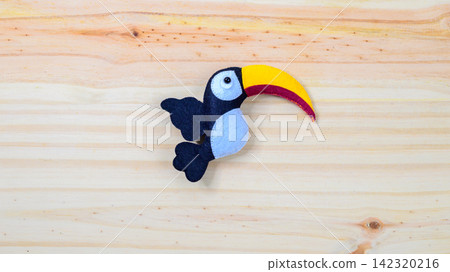 Cute handmade toucan bird on a wooden background with copy space Cute handmade toucan bird on a wooden background with copy space 142320216
