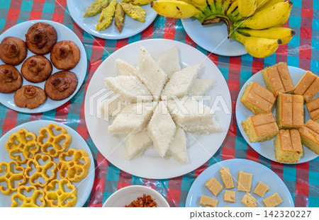 Traditional Sinhala-Tamil New Year table with milk rice, Sri Lankan sweets, cakes, bananas, and homemade treats arranged on plates Traditional Sinhala-Tamil New Year table with milk rice, Sri Lankan sweets, cakes, bananas, and homemade treats arranged on plates 142320227
