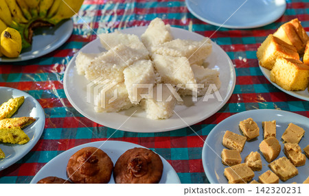 Traditional Sinhala-Tamil New Year table with milk rice, Sri Lankan sweets, cakes, bananas, and homemade treats arranged on plates Traditional Sinhala-Tamil New Year table with milk rice, Sri Lankan sweets, cakes, bananas, and homemade treats arranged on plates 142320231