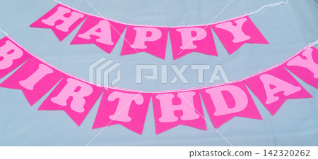 Pink happy birthday pennant banner arranged as a festive party decoration on a light background Pink happy birthday pennant banner arranged as a festive party decoration on a light background 142320262
