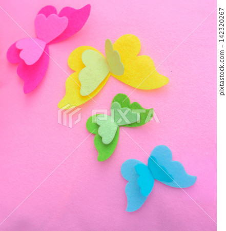 Colorful handmade felt butterflies in pink, yellow, green, and blue arranged on a soft pink pillow background Colorful handmade felt butterflies in pink, yellow, green, and blue arranged on a soft pink pillow background 142320267