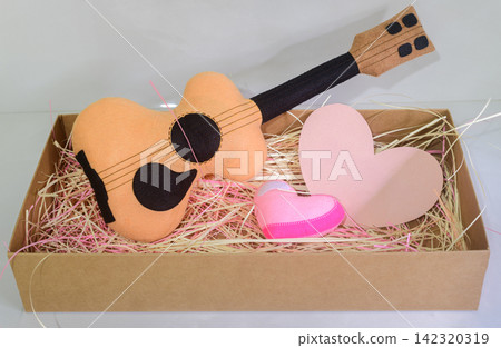 Handmade guitar gift arrangement placed in a kraft box. Heart-shaped paper with copy space for adding a text message, greeting, or personalized message for love or friendship Handmade guitar gift arrangement placed in a kraft box. Heart-shaped paper with copy space for adding a text message, greeting, or personalized message for love or friendship 142320319