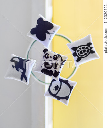 Cot mobile with cute felt animal decorations, a panda, penguin, turtle, whale, and butterfly, arranged around a circular frame view from below Cot mobile with cute felt animal decorations, a panda, penguin, turtle, whale, and butterfly, arranged around a circular frame view from below 142320321