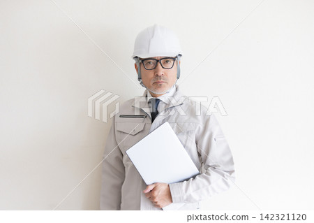 A senior construction engineer wearing a helmet and holding a laptop computer. 142321120
