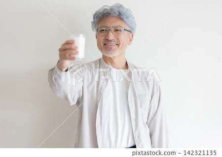 一位老人手捧一盒牛奶,面帶微笑,展現了他健康的生活方式。 一位老人手捧一盒牛奶,面帶微笑,展現了他健康的生活方式。 142321135