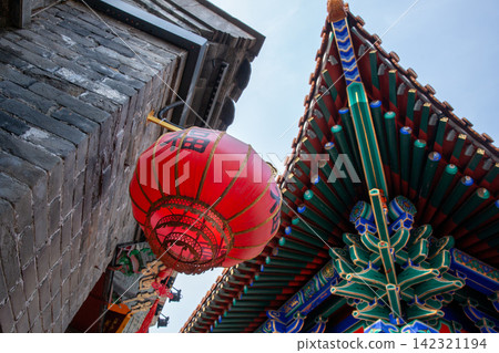 red lantern with Fu character hanging on grey brick wall under colorful eaves red lantern with Fu character hanging on grey brick wall under colorful eaves 142321194