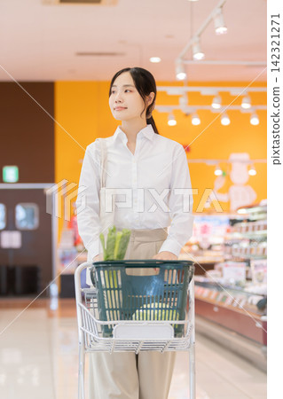 A young woman is looking for products while pushing a shopping cart in a supermarket. A young woman is looking for products while pushing a shopping cart in a supermarket. 142321271