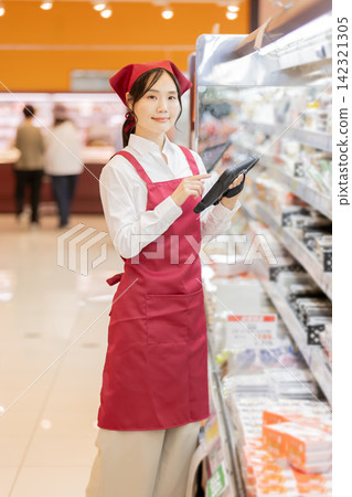 一名女店員使用平板電腦管理超市貨架上的庫存。 142321305