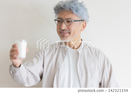 A senior man smiling with a carton of milk, showcasing his healthy lifestyle. A senior man smiling with a carton of milk, showcasing his healthy lifestyle. 142321339