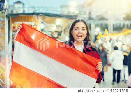 Happy girl with Austrian flag waving at New Year fair Happy girl with Austrian flag waving at New Year fair 142321558
