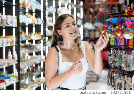 Interested young woman viewing souvenirs symbolizing Barcelona Interested young woman viewing souvenirs symbolizing Barcelona 142321568