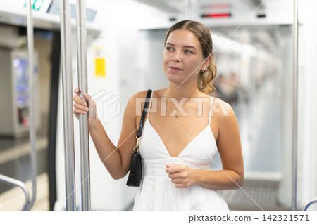 Young woman in dress standing in subway car Young woman in dress standing in subway car 142321571