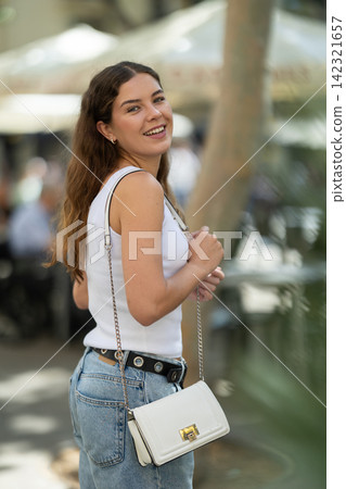 Young woman turning back with smile on summer city street Young woman turning back with smile on summer city street 142321657