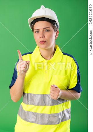 Female foreman in reflective polo shirt and hard helmet talks and discusses with someone on green background. Chroma key compositing Female foreman in reflective polo shirt and hard helmet talks and discusses with someone on green background. Chroma key compositing 142321659