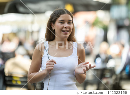 Young brunette walking past street cafe in summer city Young brunette walking past street cafe in summer city 142322166