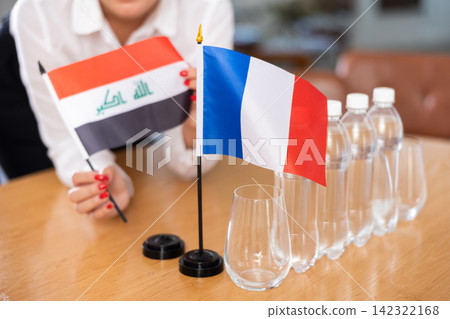 Flags of Iraq and France stand on negotiating table in office Flags of Iraq and France stand on negotiating table in office 142322168