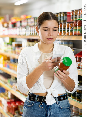 in supermarket girl scans qr code from tomato sauce label in supermarket girl scans qr code from tomato sauce label 142322250