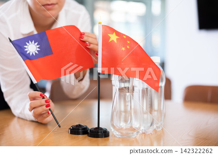 Unrecognizable girl sets midget flags of China and Taiwan before international negotiations Unrecognizable girl sets midget flags of China and Taiwan before international negotiations 142322262