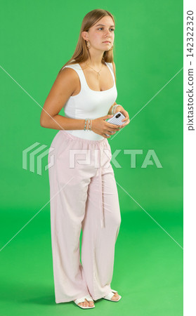 Teenage girl looking around in front of green screen Teenage girl looking around in front of green screen 142322320