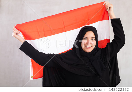 smiling Muslim woman in traditional black hijab holds flag of Austria smiling Muslim woman in traditional black hijab holds flag of Austria 142322322