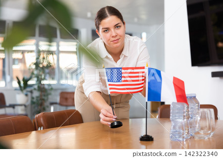 Young female assistant putting up french and south american on table for international negotiations Young female assistant putting up french and south american on table for international negotiations 142322340