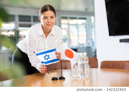 Woman placing flags of Israel and Japan on table before international meeting Woman placing flags of Israel and Japan on table before international meeting 142322403