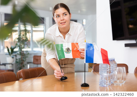 Employee of delegation prepares negotiating table - sets up flag of Mexico and France Employee of delegation prepares negotiating table - sets up flag of Mexico and France 142322460