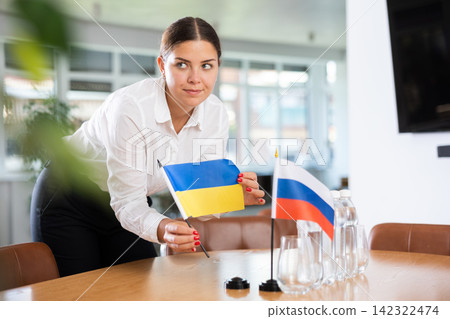 Young lady sets miniatures flags of Russia and Ukraine before international negotiations Young lady sets miniatures flags of Russia and Ukraine before international negotiations 142322474