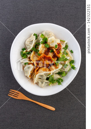 spicy Chinese dumplings with chili oil coriander and sesame seeds in a white bowl 142322531