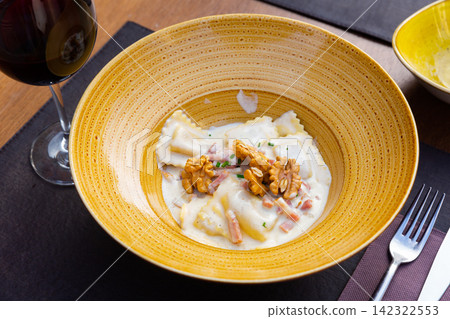 Goat cheese ravioli with carbonara sauce and walnuts Goat cheese ravioli with carbonara sauce and walnuts 142322553