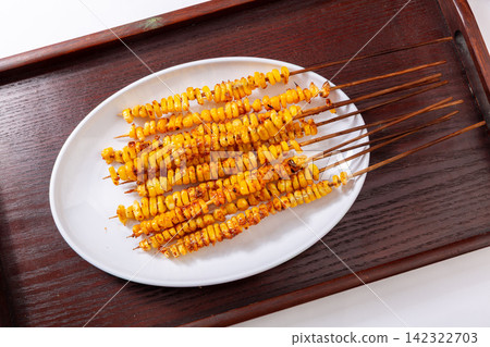 asian style grilled sweet corn skewers seasoned with spices on tray 142322703