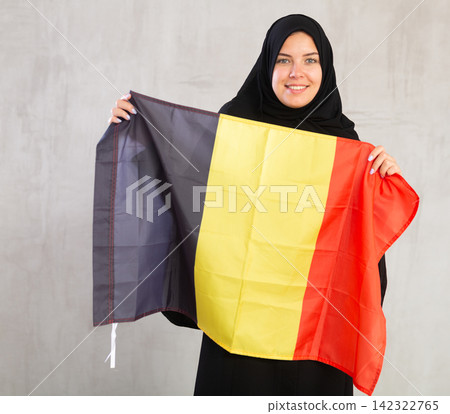 Happy young woman dressed in traditional islamic clothes with belgian flag Happy young woman dressed in traditional islamic clothes with belgian flag 142322765