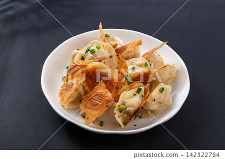 crisp pan fried dumplings guotie topped with chopped green onion crisp pan fried dumplings guotie topped with chopped green onion 142322784