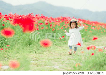 一個3歲的小女孩在罌粟田玩耍。 一個3歲的小女孩在罌粟田玩耍。 142323014
