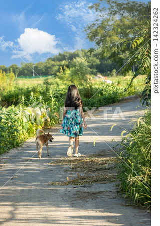 Rear view of Asian little girl walking dog on rural path, peaceful countryside lifestyle and childhood exploration concept Rear view of Asian little girl walking dog on rural path, peaceful countryside lifestyle and childhood exploration concept 142324262