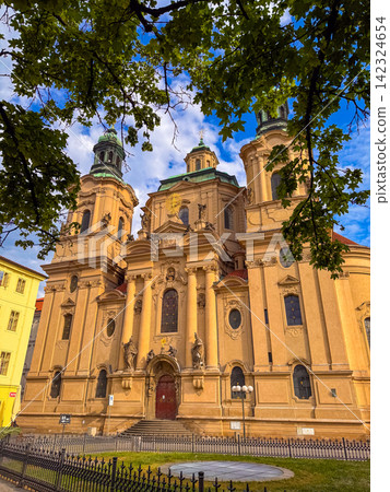 Historic church stands tall under the blue sky with people walking nearby 142324654