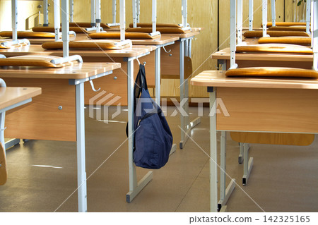 Blue Backpack Hanging on Wooden Desk in Empty School Classroom During Daytime Blue Backpack Hanging on Wooden Desk in Empty School Classroom During Daytime 142325165