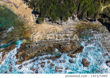 Aerial view of clear turquoise ocean water and rugged rocky coastline at Brooms Head, showcasing the natural coastal landscape and distinctive rock formations along the Clarence Valley coastline Aerial view of clear turquoise ocean water and rugged rocky coastline at Brooms Head, showcasing the natural coastal landscape and distinctive rock formations along the Clarence Valley coastline 142325940