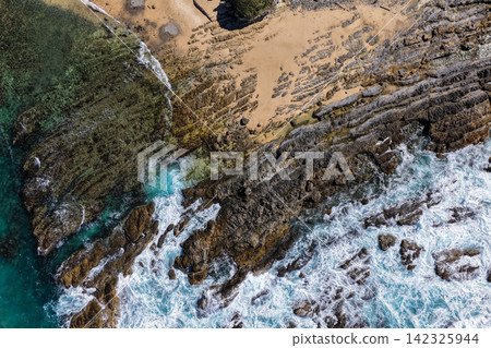 Aerial view of clear turquoise ocean water and rugged rocky coastline at Brooms Head, showcasing the natural coastal landscape and distinctive rock formations along the Clarence Valley coastline Aerial view of clear turquoise ocean water and rugged rocky coastline at Brooms Head, showcasing the natural coastal landscape and distinctive rock formations along the Clarence Valley coastline 142325944