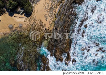 Aerial view of clear turquoise ocean water and rugged rocky coastline at Brooms Head, showcasing the natural coastal landscape and distinctive rock formations along the Clarence Valley coastline Aerial view of clear turquoise ocean water and rugged rocky coastline at Brooms Head, showcasing the natural coastal landscape and distinctive rock formations along the Clarence Valley coastline 142325946