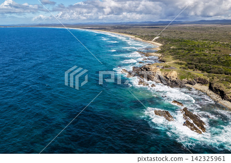Aerial view of the Brooms Head headland surrounded by the Pacific Ocean, with the long sandy shoreline of Sand Dune Beach stretching along the coast and surrounding natural landscape in the Clarence Aerial view of the Brooms Head headland surrounded by the Pacific Ocean, with the long sandy shoreline of Sand Dune Beach stretching along the coast and surrounding natural landscape in the Clarence 142325961