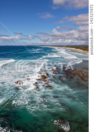 Vertical aerial view of the rugged headland and rocky coastline at Brooms Head with the long sandy shoreline of Sand Dune Beach, Pacific Ocean and surrounding natural coastal landscape on the NSW Vertical aerial view of the rugged headland and rocky coastline at Brooms Head with the long sandy shoreline of Sand Dune Beach, Pacific Ocean and surrounding natural coastal landscape on the NSW 142325972