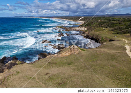 Aerial view of the rugged headland and rocky coastline at Brooms Head on the NSW North Coast, featuring exposed coastal rock formations, Pacific Ocean and native vegetation along the scenic Clarence Aerial view of the rugged headland and rocky coastline at Brooms Head on the NSW North Coast, featuring exposed coastal rock formations, Pacific Ocean and native vegetation along the scenic Clarence 142325975