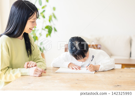 A girl and her mother studying in the living room A girl and her mother studying in the living room 142325993