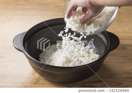 將生米放入陶罐中;準備煮飯。 將生米放入陶罐中;準備煮飯。 142326069