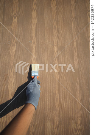 Hand holding paintbrush on wooden surface Hand holding paintbrush on wooden surface 142326974