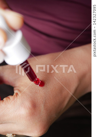 Close-Up Dropper Applying Red Blood Drop To Skin For Medical Test Or Wound Care Close-Up Dropper Applying Red Blood Drop To Skin For Medical Test Or Wound Care 142327095