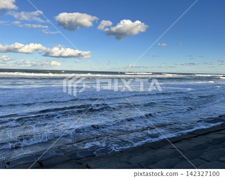 千葉縣九十九里海灘洶湧的白色海浪和藍天中漂浮的白雲。 千葉縣九十九里海灘洶湧的白色海浪和藍天中漂浮的白雲。 142327100