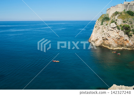 克羅埃西亞杜布羅夫尼克海岸,碧藍的海面上漂浮著皮划艇,俯瞰著海岬上的堡壘。 克羅埃西亞杜布羅夫尼克海岸,碧藍的海面上漂浮著皮划艇,俯瞰著海岬上的堡壘。 142327248